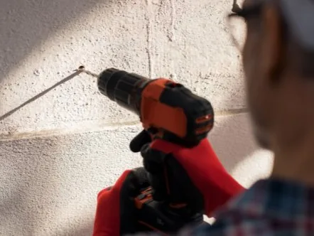 Mann bohrt mit dem Akkuschrauber in die Wand