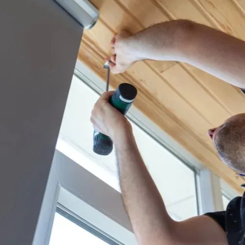 Handwerker bohrt in eine Holzdecke