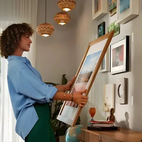 Frau hängt ein großes Bild auf