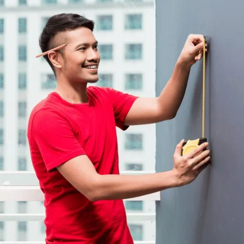 Mann misst an der Außenwand die Position aus