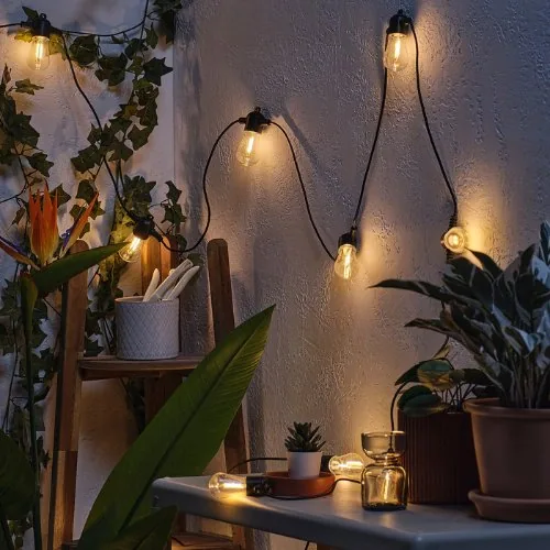 Outdoor-Lichterkette an der Hauswand über der Terrasse
