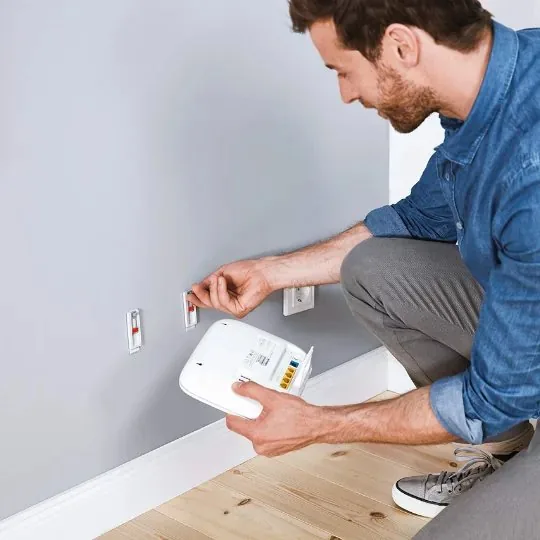 Mann hängt einen Router an die Wand