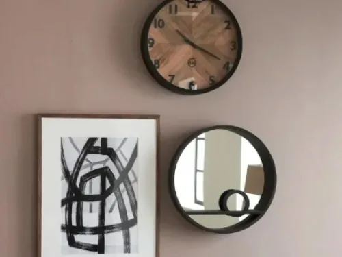 Runder Spiegel, Wanduhr und Bild an einer altrosa Wand