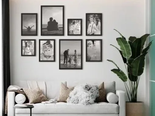 Schwarze Rahmen mit Schwarz-Weiß-Fotos über einem hellen Sofa