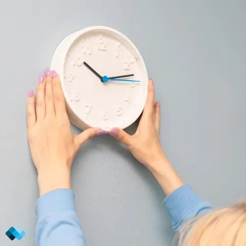 Hände halten eine Wanduhr an die Wand