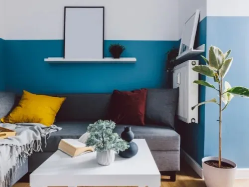 WG-Zimmer einrichten: kleines Zimmer mit blauer Wand, Sofa und Wandboard